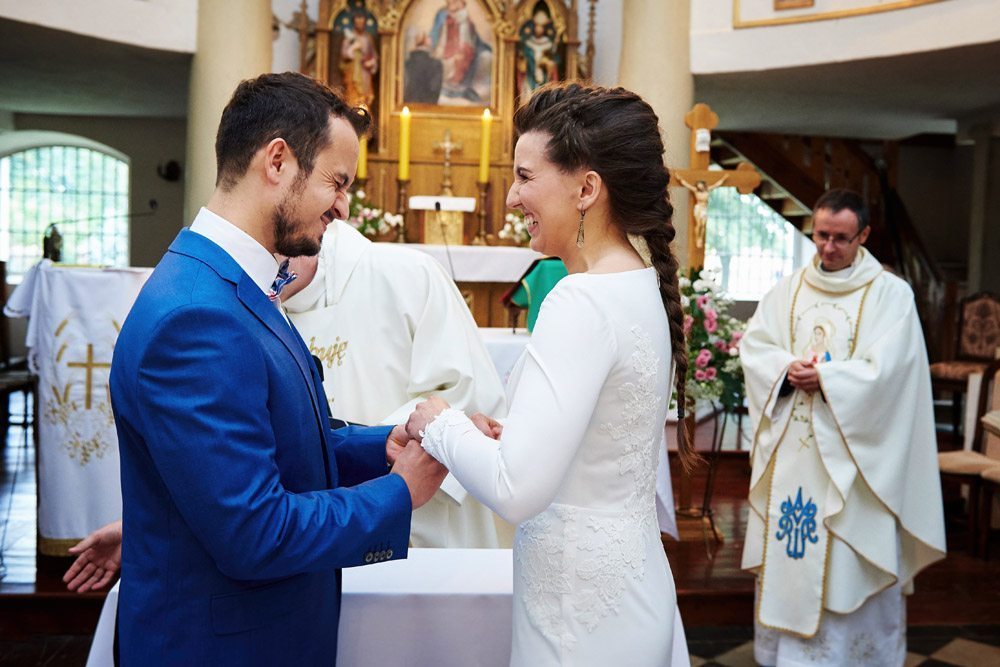 uśmiechnięta para młoda przy zakładaniu obrączek - zdjęcia ślubne wrocław
